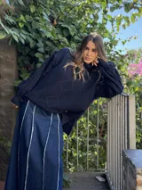 Sweater de punto color azul marino con cuello alto, diseño de rombos en relieve y detalles de flecos en las costuras de las mangas. Presenta un corte holgado con aberturas laterales en el ruedo.