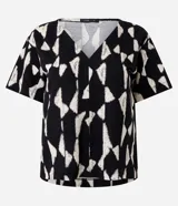 Blusa de manga corta con escote en V y un estampado geométrico abstracto en blanco y negro.