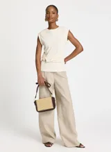 Musculosa color crema de algodón con cuello redondo y tirantes anchos. Presenta una banda fruncida en el frente con detalle de argolla metálica lateral.