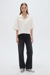 Blusa de lino color natural, con cuello polo y escote en V, de mangas cortas holgadas y corte recto.