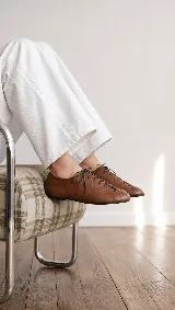 Zapato acordonado tipo oxford de cuero color off-white, con punta cuadrada, costuras decorativas y cordones finos al tono.
