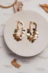 Aros dorados con forma de argolla curva y pequeñas gotas metálicas móviles. Fabricados en acero quirúrgico con baño de oro de 18k.