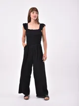 Mono largo negro con breteles finos, cuerpo superior fruncido y pantalón palazzo.