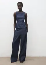 Top sin mangas de efecto denim con cuello redondo y diseño ajustado en la cintura con ligero vuelo en el bajo. Cuenta con cierre de botón en la parte posterior del cuello.