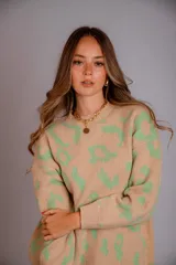 Buzo de punto color beige con estampado de manchas irregulares en verde claro, cuello redondo y manga larga.