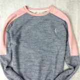 Buzo gris con mangas y cuello rosado claro, confeccionado en algodón rústico.