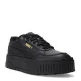 Championes urbanos Puma modelo Karmen II Idol, color negro con detalles en dorado. Presentan una suela de plataforma robusta con diseño texturizado, cierre de cordones y logo de la marca en el lateral.