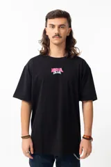 Remera negra de algodón con estampado en la espalda que dice "THE EARTH IS FLAT" y un dibujo de un hombre con micrófono parado sobre una tierra plana.