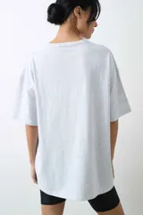 Remera de algodón gris melange con corte oversize, manga corta y estampa localizada en el frente con motivos deportivos en tonos verde y rosado.