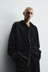 Sobrecamisa de corte relajado confeccionada en tejido de terciopelo elástico, con cuello solapa, manga larga con puños abotonados y cierre frontal de botones.