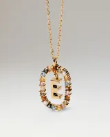 Collar dorado con cadena de eslabones y un dije circular decorado con cristales multicolor y una letra E tridimensional colgando en el centro.