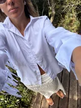 Camisa blanca de mangas largas con flecos en la espalda y en las mangas.