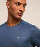 Remera deportiva de poliéster color gris claro, con cuello redondo, mangas cortas y recortes laterales de poliamida. Corte clásico.