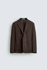 Blazer de corte regular fit confeccionado en tejido de lana, con cuello de solapas de muesca, manga larga con puños abotonados, bolsillos de vivo en el pecho y de plastrón en la cadera, cierre frontal de un botón y aberturas en la espalda.