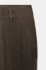 Pantalón flare de tiro medio confeccionado en lino color marrón. Cuenta con cintura con trabillas, bolsillos delanteros, perneras de corte evasé y cierre frontal con cremallera y botón.