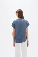 Blusa de viscosa color blanco, de corte holgado, con cuello en V y cierre frontal parcial de botones grandes con efecto carey.