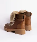 Borcegos de cuero vacuno en tonos marrón, con diseño de caña media y cuello con forro de piel sintética negra. Presentan cordones marrones, ganchos metálicos para ajuste y suela de goma tipo track con plataforma.
