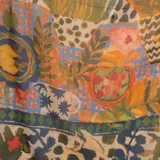 Pashmina con estampado multicolor de inspiración artística y floral, con predominio de tonos azules, rojos y amarillos, y bordes en azul marino.
