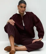 Campera estilo bomber de sarga color bordó, con cuello alto, cierre frontal con botones forrados, mangas largas con puños elásticos y bajo ajustado.