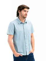 Camisa de manga corta color celeste claro, confeccionada en algodón, con cuello clásico y un bolsillo de parche en el lado izquierdo del pecho.