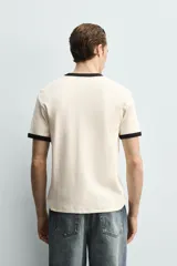 Camiseta de corte regular fit, color gris oscuro, con cuello redondo y bordes de mangas en color azul marino a contraste.
