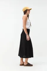 Falda midi de lino color beige, de tiro alto y corte recto, con abertura delantera y cierre cruzado sutil.