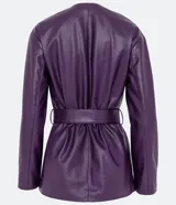 Campera alargada marca Cortelle confeccionada en poliuretano con textura que imita el cuero. Presenta cuello redondo, cierre frontal con botones metálicos, cuatro bolsillos delanteros con solapa y botones, y un lazo ajustable en la cintura.