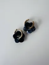 Aros de acero quirúrgico dorados con dije colgante en forma de flor de resina marmolada en tonos negro y blanco.