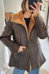 Campera reversible de cuero genuino napalán color negro, con cuello y detalles de corderito sintético, cierre frontal y bolsillos ribeteados.