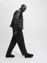 Pantalón negro de tiro alto y corte wide leg, con pliegues frontales y confeccionado en algodón.