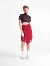 Falda larga cruzada de tencel color rojo, ajustable con tiras laterales y detalles de encaje en el borde inferior y la cintura.