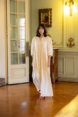 Vestido largo de muselina color crema, con silueta amplia y fluida. Presenta cuello en V, cierre frontal con botones y mangas largas relajadas.