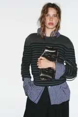 Bolso de hombro con acabado efecto craquelado en color marrón oscuro. Presenta doble asa de hombro, cierre superior con cremallera y detalles metálicos dorados en la parte frontal y laterales.