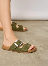 Sandalia chata de gamuza color marrón topo, con dos tiras anchas en el empeine y una hebilla metálica grande rectangular plateada como detalle. Suela plana marrón.