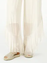 Pantalón palazzo color crema, de seda con volados en el ruedo.