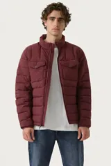 Campera puffer acolchada color bordó, con cierre frontal, cuello alto y dos bolsillos frontales con solapa y botón a presión.