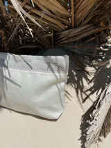 Sobre de mano color plateado con acabado texturizado y cierre superior. Incluye una correa de muñeca personalizada con la marca Rupia y detalles en yute.