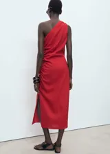 Vestido midi de diseño recto con cuello asimétrico de un solo hombro. Presenta un detalle de fruncido lateral y una abertura en el bajo. Confeccionado en una mezcla de lyocell y lino.