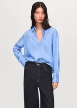 Camisa de corte recto y diseño a rayas verticales, con cuello camisero, cierre frontal de botones y mangas largas con puños abotonados.