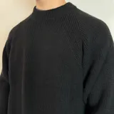 Sweater verde oliva de tejido grueso con cuello alto y mangas raglán. Corte holgado.