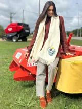 Ruana de color crudo con textura acanalada y escudo nacional bordado en la parte inferior.