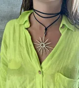 Gargantilla de cuero negro con dije grande en forma de sol dorado.