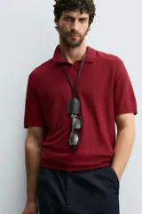 Polo de manga corta color bordó, con cuello solapa y abertura frontal. Tejido de punto con estructura acanalada.