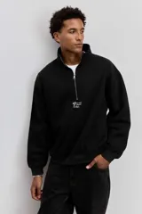 Buzo de cuello alto con cierre frontal parcial, de corte holgado y diseño minimalista con pequeño estampado central en el pecho.