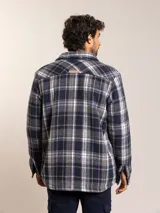 Camisa tipo campera de franela con estampado a cuadros en tonos azul, gris y blanco. Cuenta con forro interior de sherpa, cierre frontal con botones, cuello clásico y bolsillo en el pecho.