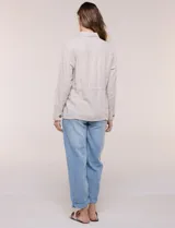 Sobrecamisa beige de lino liviano, con cuello camisero, cierre frontal de botones carey y bolsillos en el pecho. Cuenta con cordón ajustable en la cintura y mangas largas.