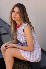 Vestido corto sin mangas con cuello redondo cerrado y estampado de rayas verticales multicolor. Presenta un cuerpo elástico fruncido tipo nido de abeja hasta la cadera y una falda con ligero vuelo.