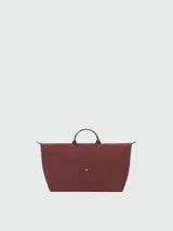 Bolso de viaje de gran tamaño, modelo Le Pliage One de Longchamp, en color marrón. Presenta el diseño icónico de la marca con solapa de cuero, asas cortas y cierre de cremallera superior.