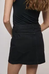 Falda de denim blanca de corte recto con bolsillos delanteros aplicados, costuras pespunteadas a contratono y cierre frontal con botón y cremallera.