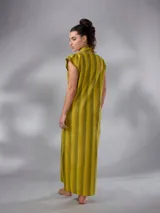 Vestido largo de lino y algodón con diseño de rayas verticales en tonos mostaza y verde. Presenta escote en V, cuello solapa ancho, mangas cortas con diseño capa, corte recto y lazo ajustable en la cintura.